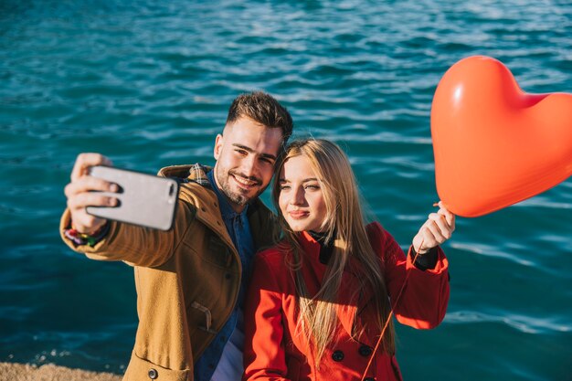 Beautiful couple posing for selfie with balloon