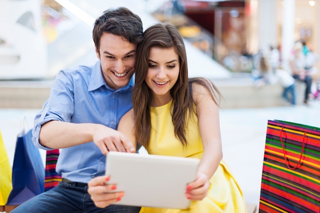 Beautiful couple in shopping mall looking on digital tablet