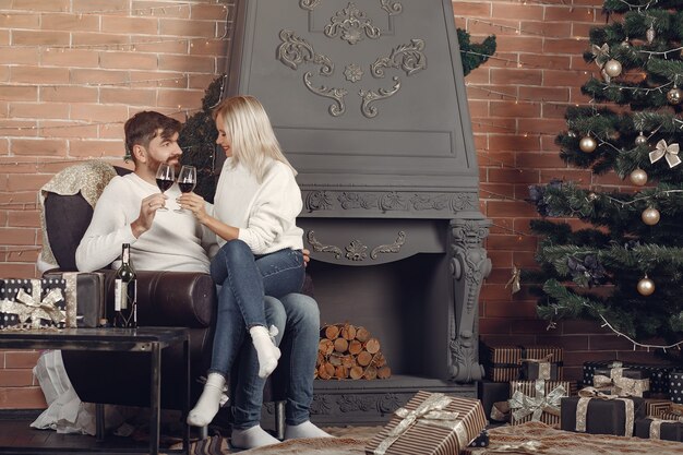 クリスマスツリーの近くに家に座っている美しいカップル