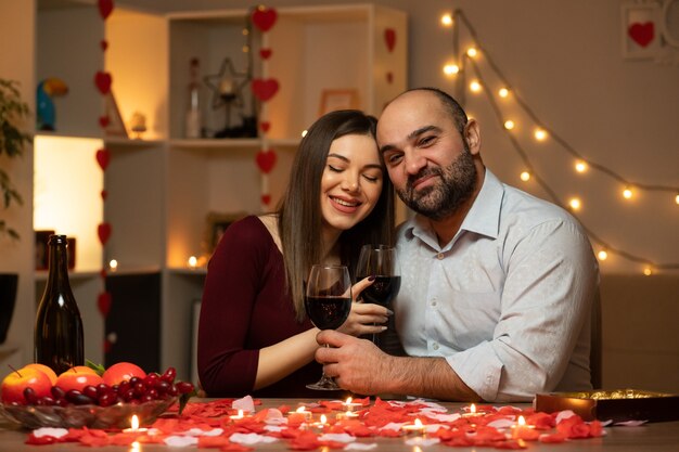 beautiful couple sitting at the table decorated with candles and rose petals, spending evening together