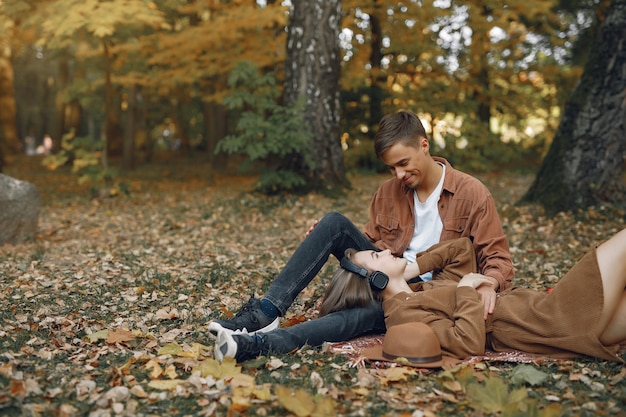 美しいカップルは秋の公園で時間を過ごす