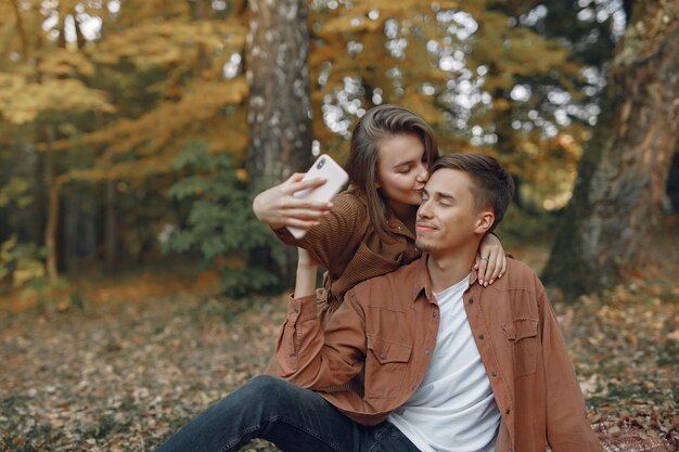 美しいカップルは秋の公園で時間を過ごす