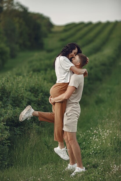 美しいカップルは夏の畑で時間を過ごす