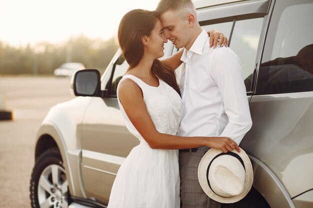 Beautiful couple spend time in a summer park near a car