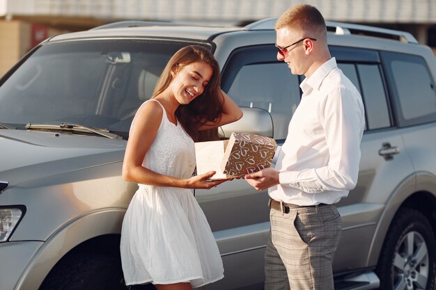 Beautiful couple spend time in a summer park near a car