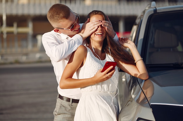 Beautiful couple spend time in a summer park near a car