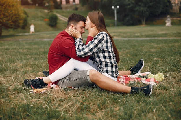 美しいカップルは夏の公園で時間を過ごす