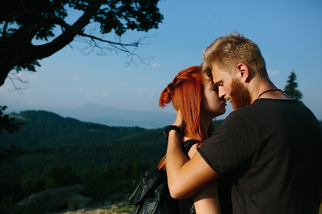 Beautiful couple standing on a hill and gently hugging each other