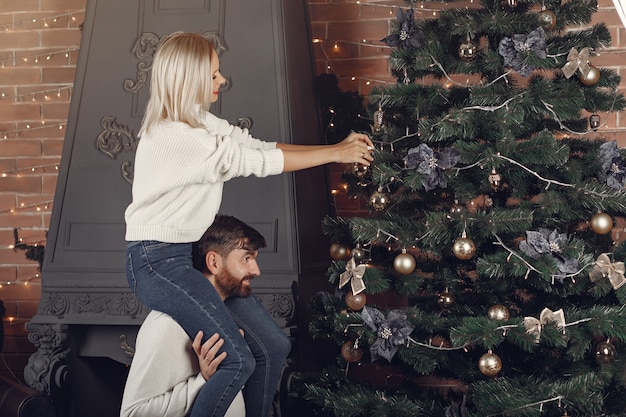 Free photo beautiful couple standing at home near christmas tree