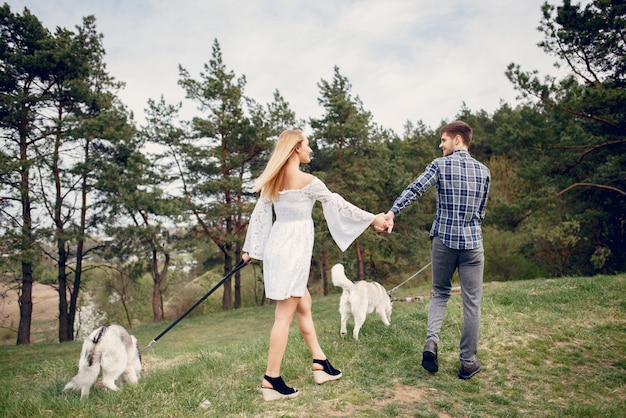 Beautiful couple in a summer forest with a dogs