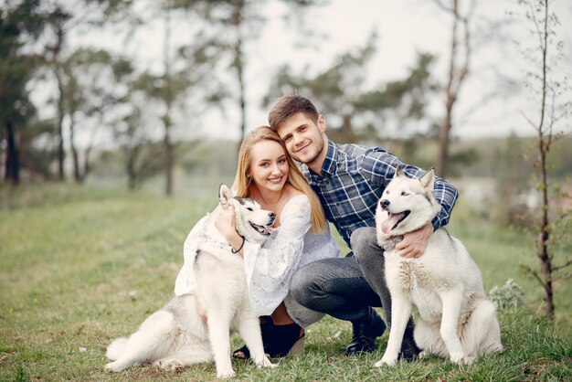 Beautiful couple in a summer forest with a dogs