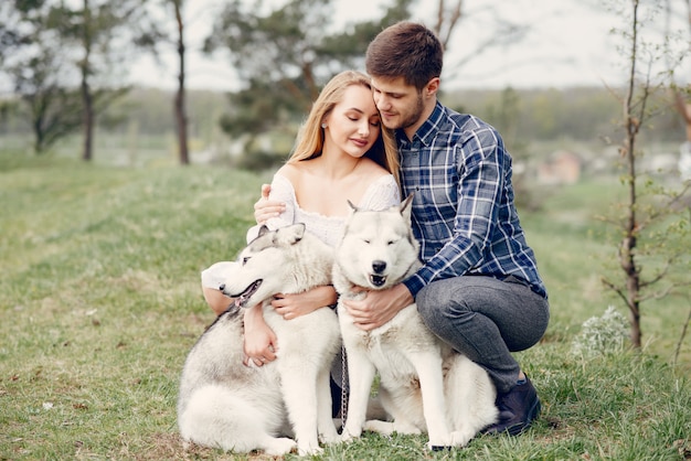 Beautiful couple in a summer forest with a dogs