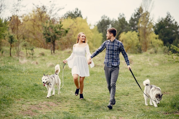 Beautiful couple in a summer forest with a dogs