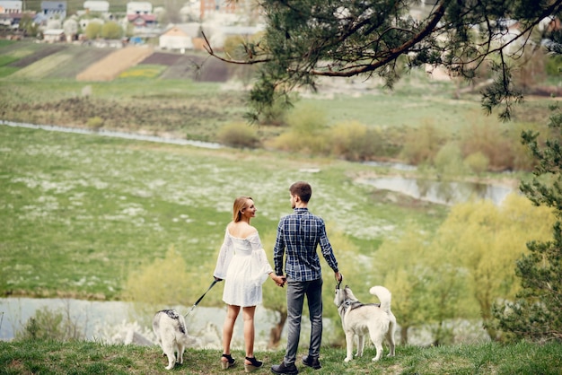 Beautiful couple in a summer forest with a dogs