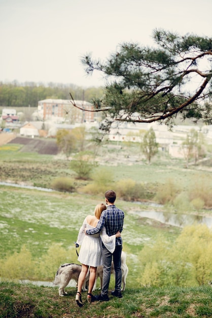 Beautiful couple in a summer forest with a dogs