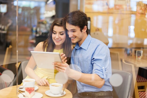 カフェでデジタルタブレットを使用して美しいカップル