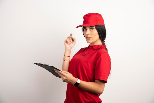 Beautiful courier with clipboard standing on white background. High quality photo