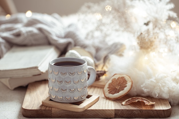 A beautiful cup with a hot drink on the background of cozy things. Home comfort and warmth concept.