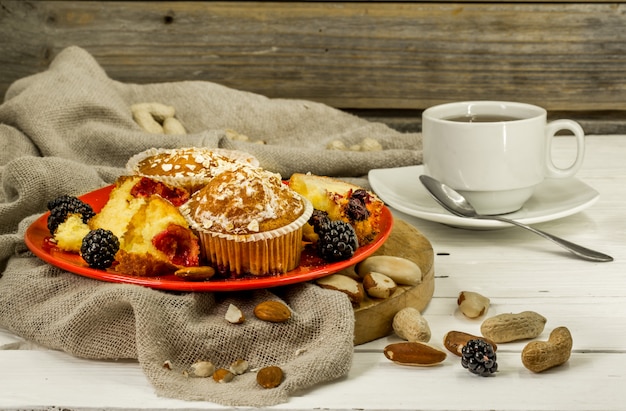 beautiful cupcakes with berries on wooden table in red plate