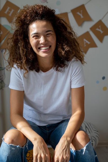 Free photo beautiful curly mestizo posing against the background of the inscription happy birthday