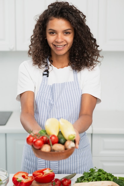 Free photo beautiful curly woman offering vegetables