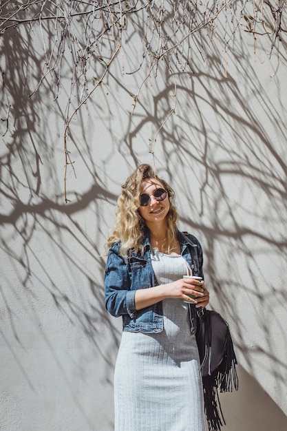 beautiful curly young woman outdoors walking and drinking coffee.