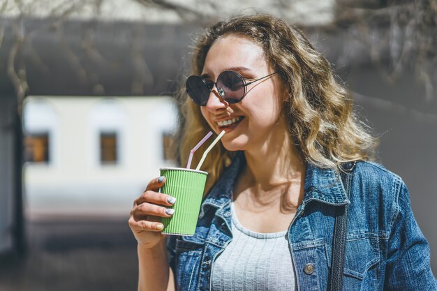 歩くこと、コーヒーを飲む、屋外で、美しい、カーリー、若い、女。