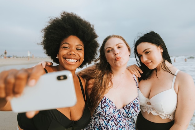 Belle donne curvy prendendo un selfie in spiaggia