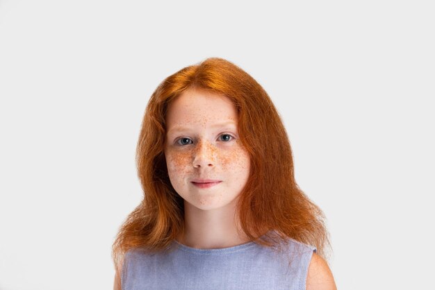 Beautiful cute little redheaded girl in casual outfit posing isolated on white studio background Happy childhood concept Sunny child