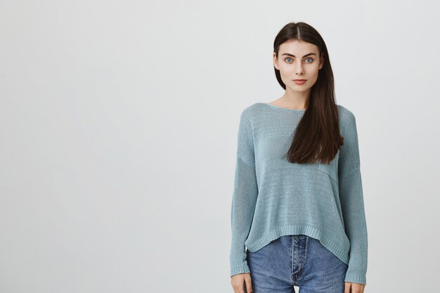 Beautiful dark-haired young woman in blue loose sweater and jeans