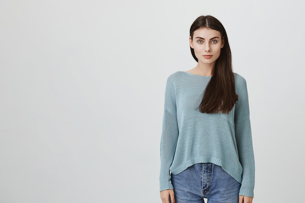 Beautiful dark-haired young woman in blue loose sweater and jeans