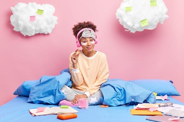 Beautiful dark skinned curly woman in comfortable pajama gesture small gesture