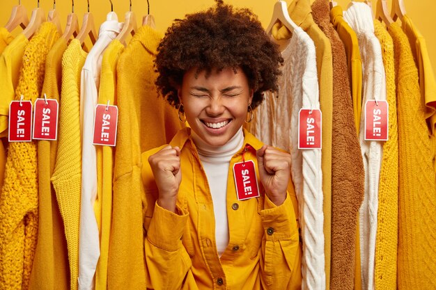 Beautiful dark skinned woman surrounded by clothes rack