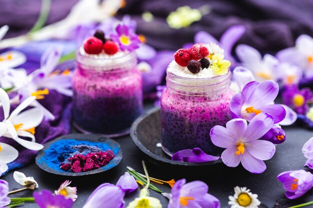 色とりどりの花で飾られた紫色の春のビーガンスムージーの美しいディスプレイ