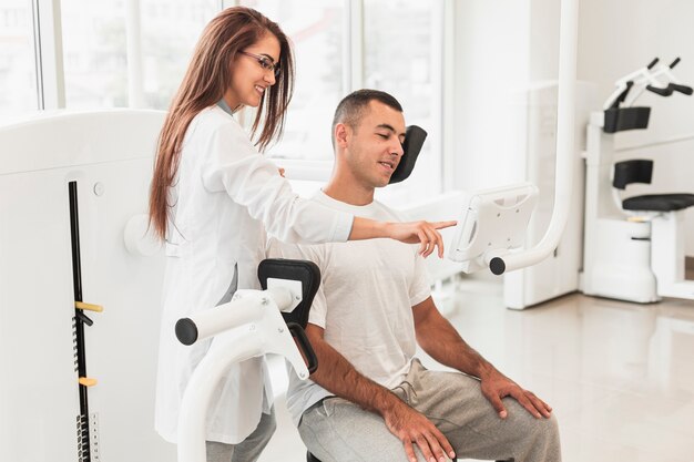 Beautiful doctor showing patient how to use medical device