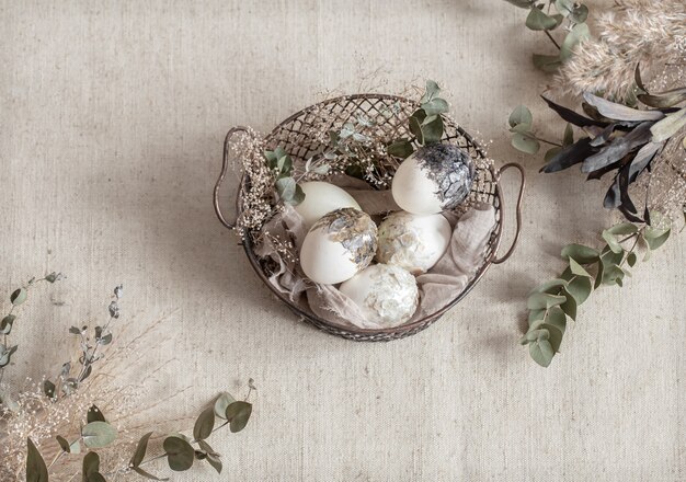 Beautiful Easter eggs in a basket decorated with dried flowers. Happy Easter concept.