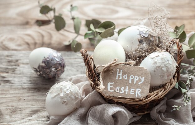 Beautiful Easter eggs in a basket decorated with dried flowers. Happy Easter concept.