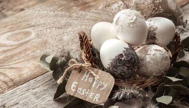 Beautiful Easter eggs in a basket decorated with dried flowers. Happy Easter concept.
