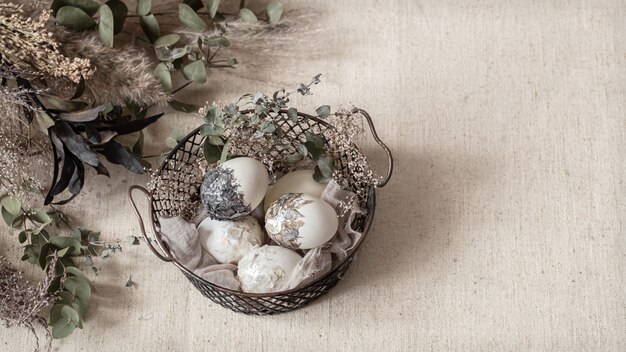 Красивые пасхальные яйца в корзине, украшенной засушенными цветами. Счастливой Пасхи концепции.
