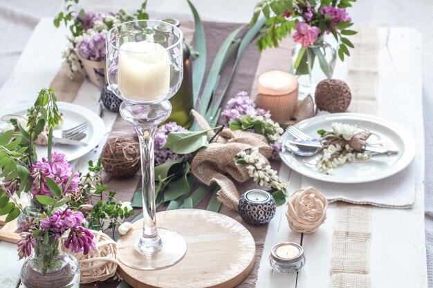 休日のための美しいエレガントな装飾が施されたテーブル-モダンなカトラリー、弓、ガラス、キャンドル、ギフトのある結婚式またはバレンタインの日