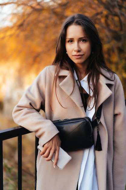 Beautiful elegant woman standing in a park in autumn