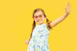 Бесплатное фото Красивая эмоциональная маленькая девочка, изолированная на желтом