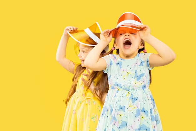 Free photo beautiful emotional little girls isolated on yellow space