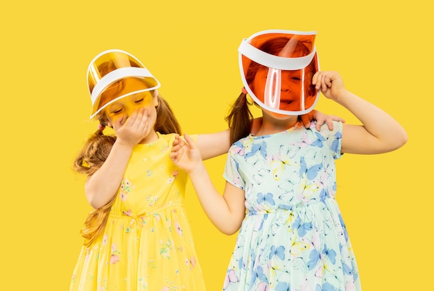 Free photo beautiful emotional little girls isolated on yellow