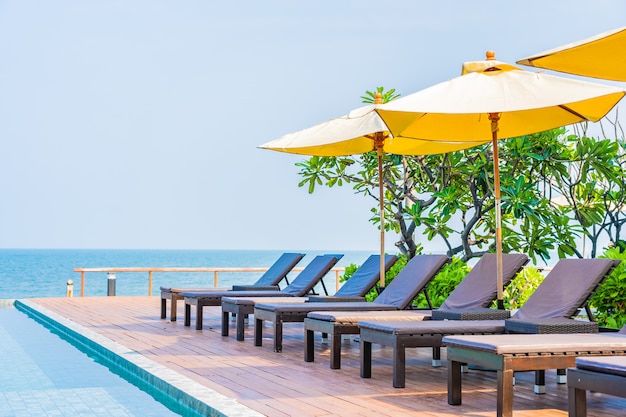 Free photo beautiful empty chairs and umbrellas around outdoor swimming pool in hotel resort