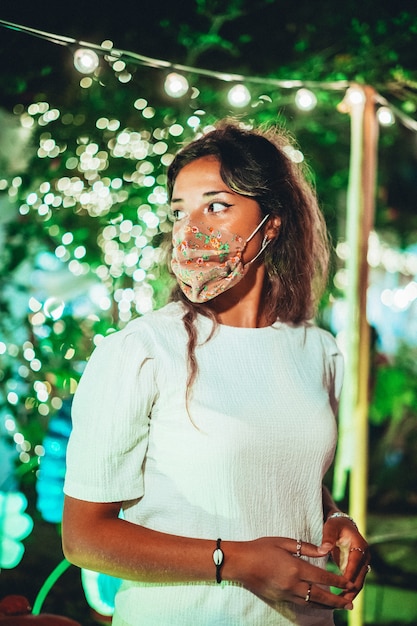 Foto gratuita bella femmina europea che indossa una maschera floreale in un parco di divertimenti