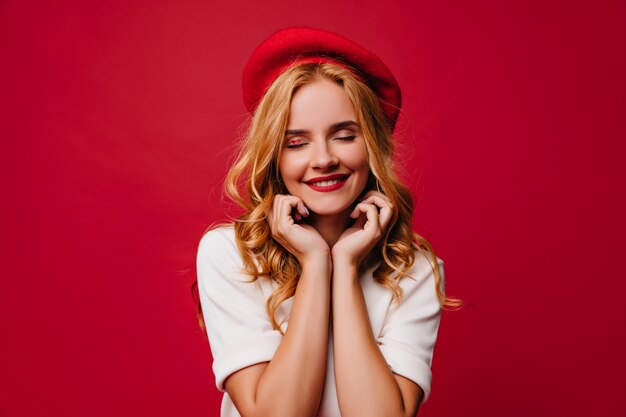 Beautiful european girl in french beret smiling. Portrait of blissful blonde lady in good mood.