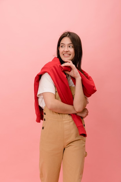 Beautiful european young brunette woman in casual clothes looks away on pink background Relaxation concept