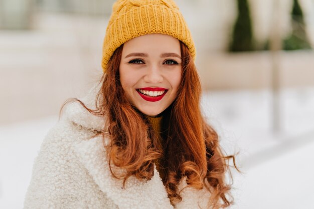 겨울에 웃 고 니트 모자에 아름 다운 유럽 젊은 여자. 세련된 코트에 관능적 인 예쁜 여자의 사진.