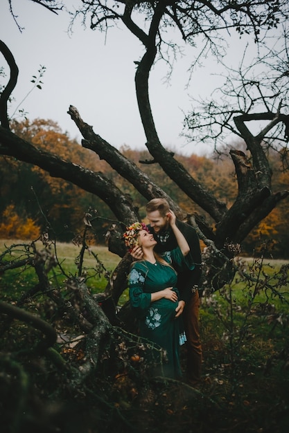 Beautiful expecting woman and her man stand hugging outside 